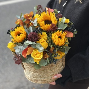 Композиция в сумке "Тональность" из подсолнухов, калл, ягод вибирнума, лимонных роз, скиммии и орхидеи в Протвино